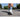 Person wearing socks with a design of a castle and a blue sky, walking on a road with trees in the background.