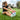 A woman in athletic wear sits on grass, stretching her legs with colorful socks. She appears focused, surrounded by a lush, green park.