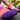 Close-up of colorful athletic socks with orange, purple, and pink patterns on feet resting on pavement. Blurred sneakers in the background. Sporty and vibrant mood.